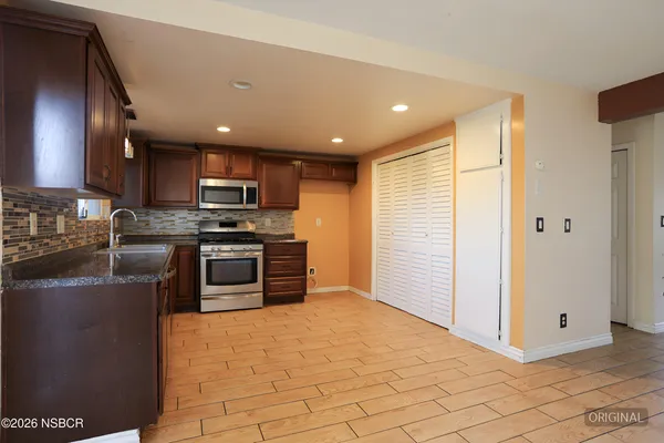 a kitchen with stainless steel appliances granite countertop wooden cabinets a stove top oven a sink and dishwasher with wooden floor