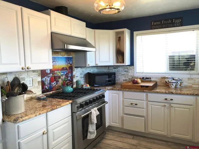 a kitchen with stainless steel appliances granite countertop a stove a sink and a microwave