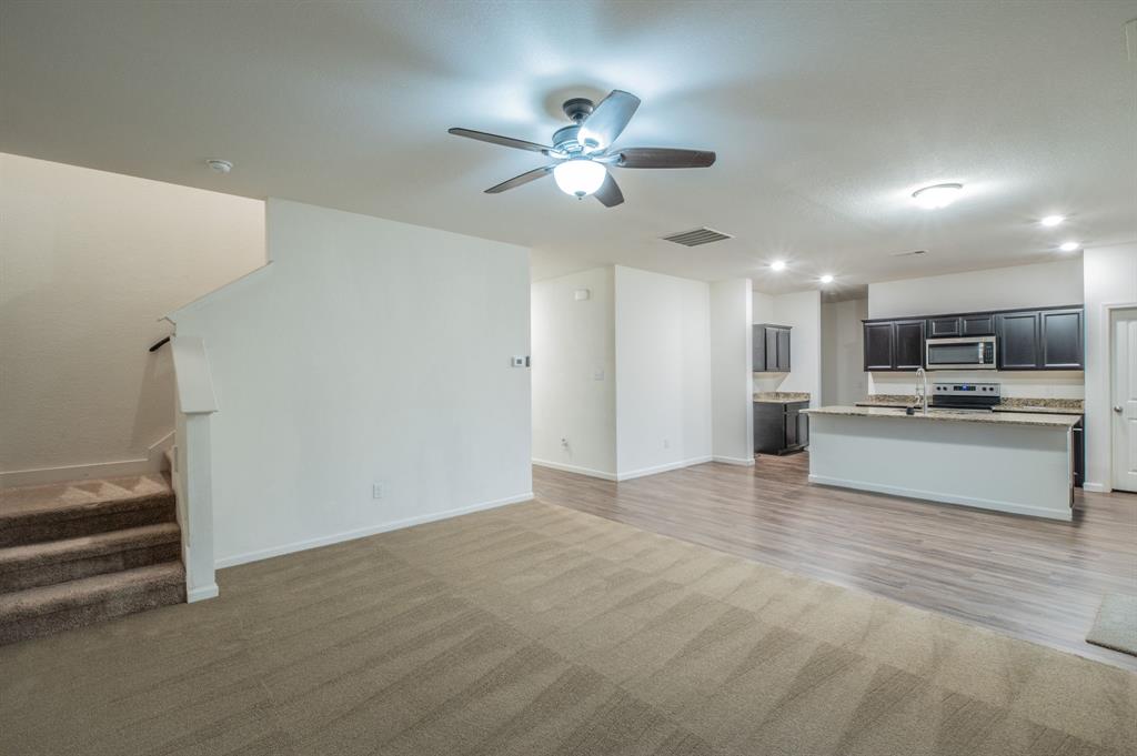 201 Sabine River Road Glenn Heights, TX 75154 - Photo 12 of 24 Open-concept living area with a ceiling fan, carpeted flooring, and a staircase with carpeted treads