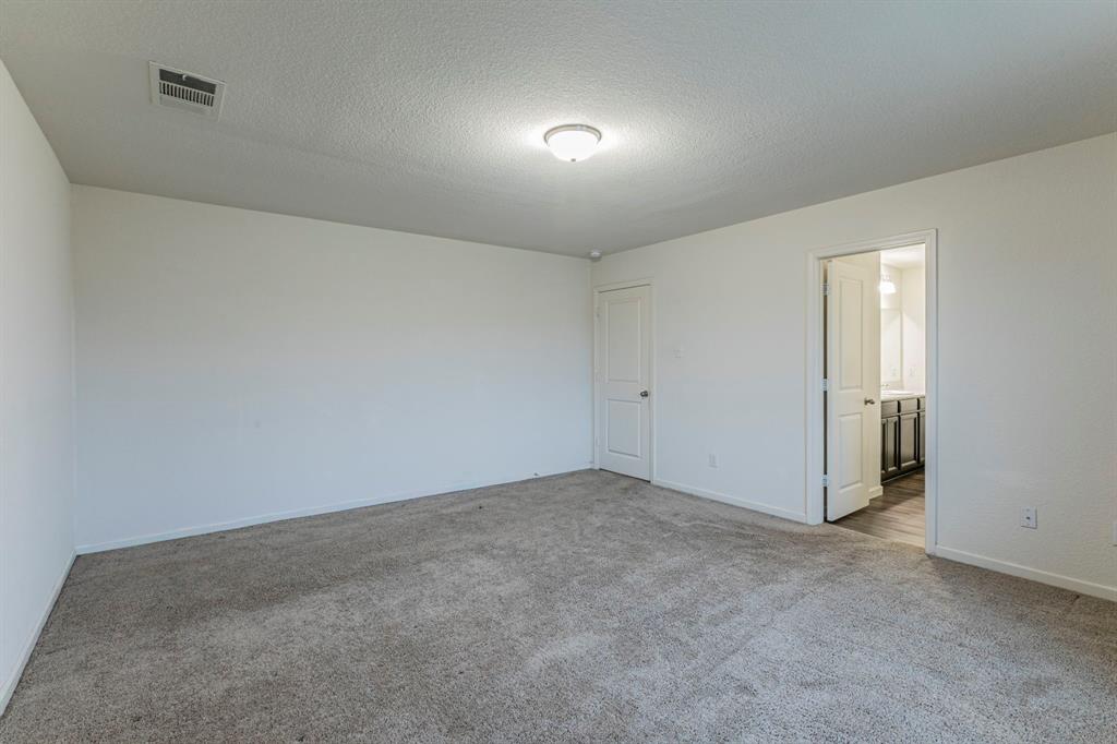 201 Sabine River Road Glenn Heights, TX 75154 - Photo 16 of 26 Unfurnished bedroom with a textured ceiling, light carpet, and connected bathroom