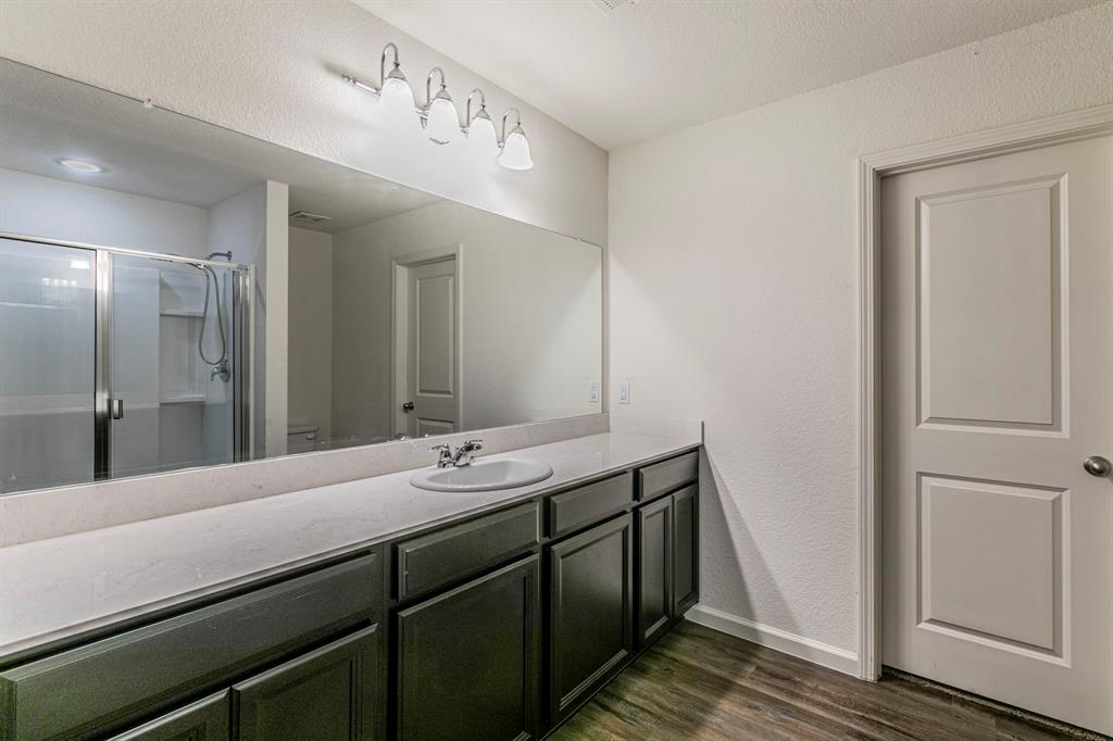 201 Sabine River Road Glenn Heights, TX 75154 - Photo 17 of 26 Full bathroom with a shower stall, vanity, dark wood-style flooring, and a textured wall