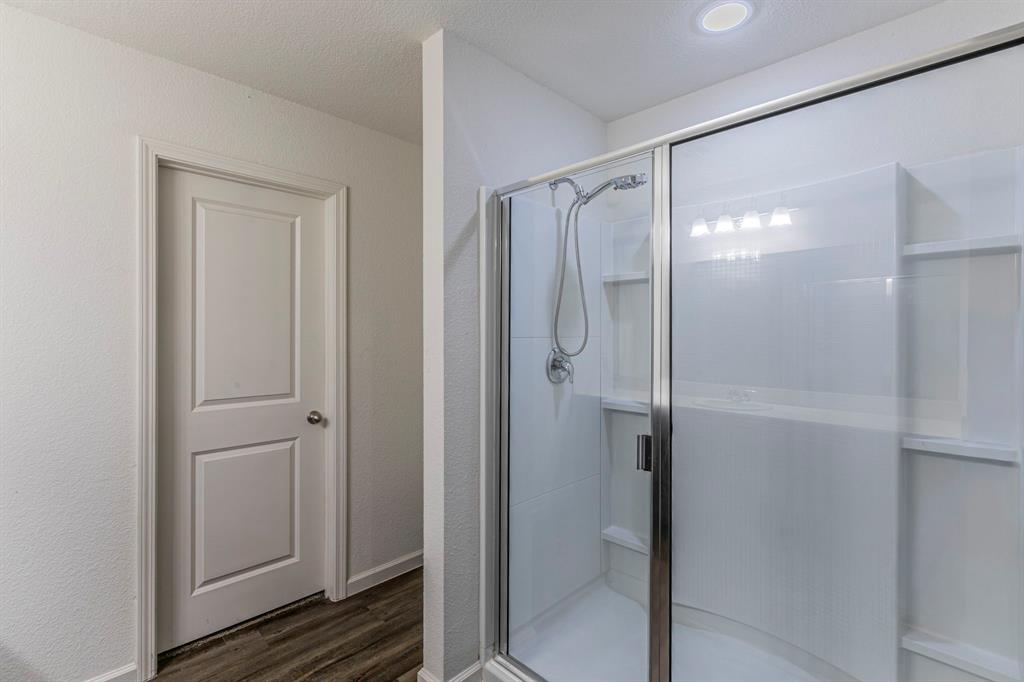 201 Sabine River Road Glenn Heights, TX 75154 - Photo 18 of 26 Bathroom with a stall shower, dark wood-type flooring, a textured ceiling, and a textured wall