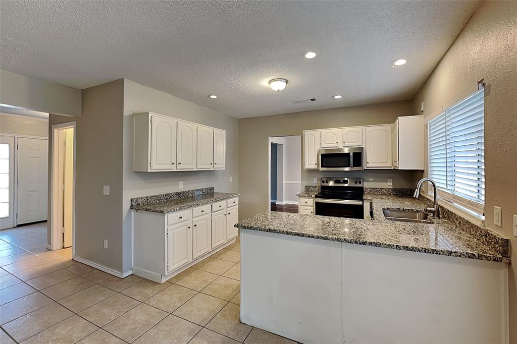 604 Ashby Place Allen, TX 75002 - Photo 4 of 21 a large kitchen with granite countertop a stove top oven a sink a granite counter space and cabinets