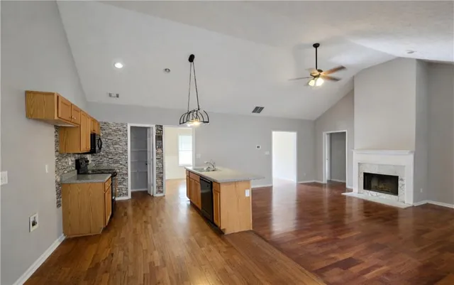 a living room with stainless steel appliances granite countertop furniture wooden floor and a fireplace