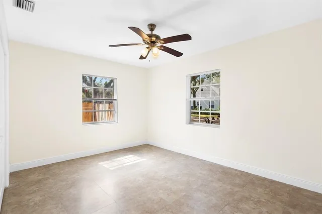 a view of empty room with window and ceiling fan