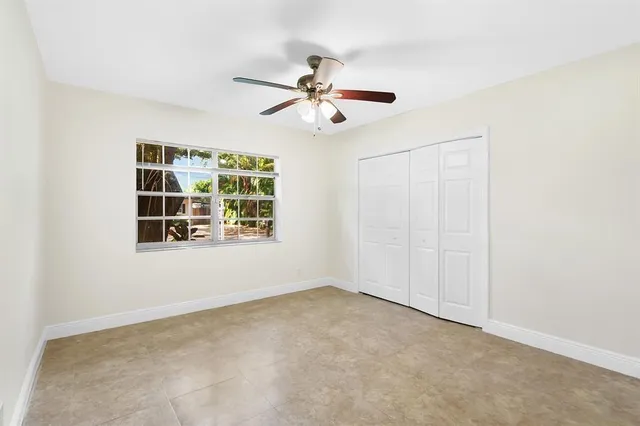 an empty room with windows and fan