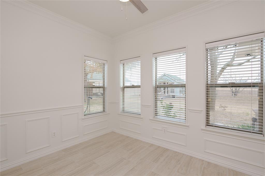 364 Parker Road, Unit A Van Alstyne, TX 75495 - Photo 15 of 39 Bright Breakfast room with a view of back acerage, featuring three tall windows with blinds, crown molding, wainscoting, and tile flooring.