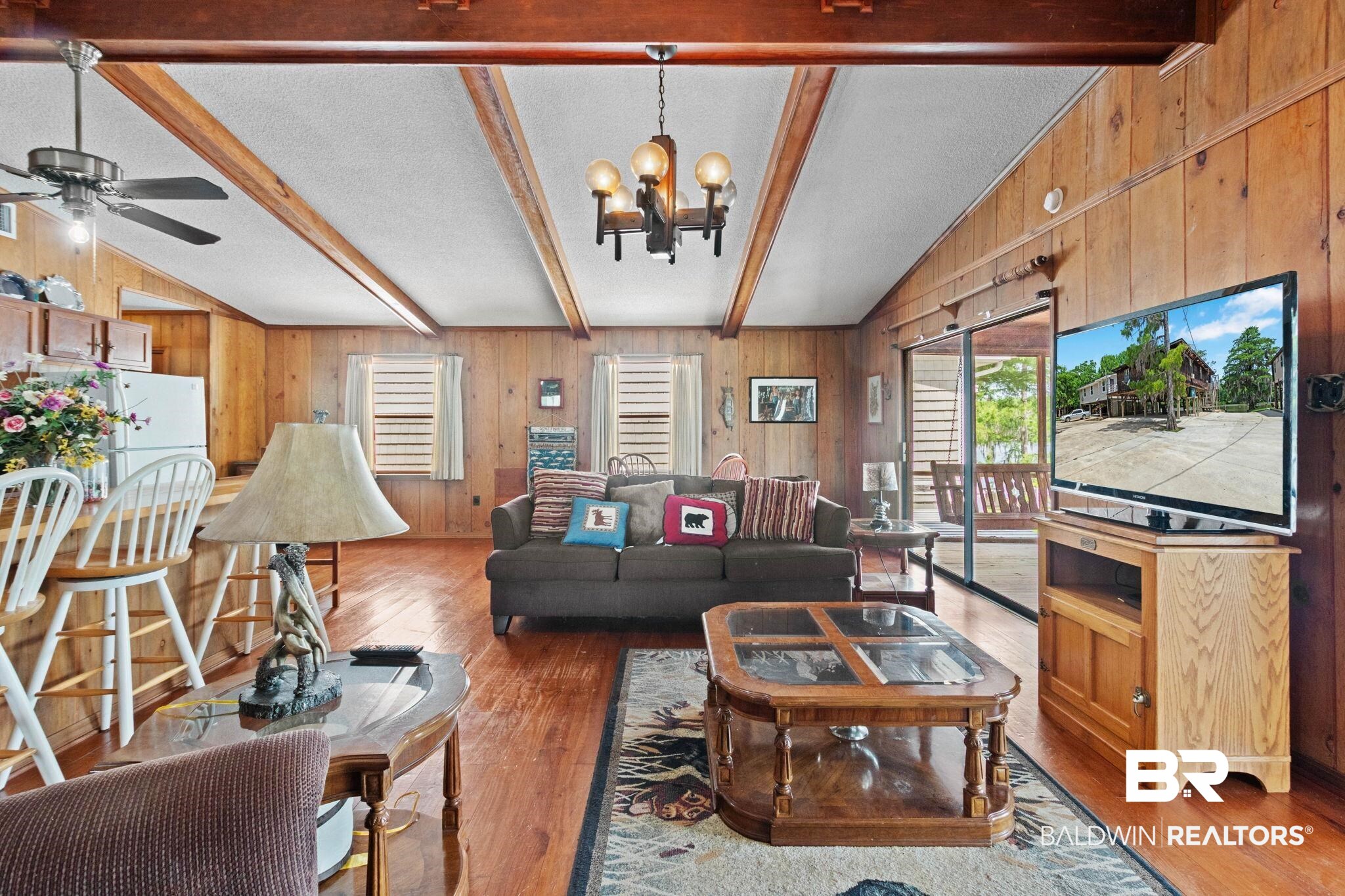 8153 Bryant's Lndg Road Stockton, AL 36579 - Photo 16 of 87 Open living area featuring wood-finish flooring, wood-paneled walls, and a vaulted ceiling with exposed wood beams