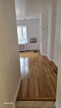a view of empty room with window and wooden floor