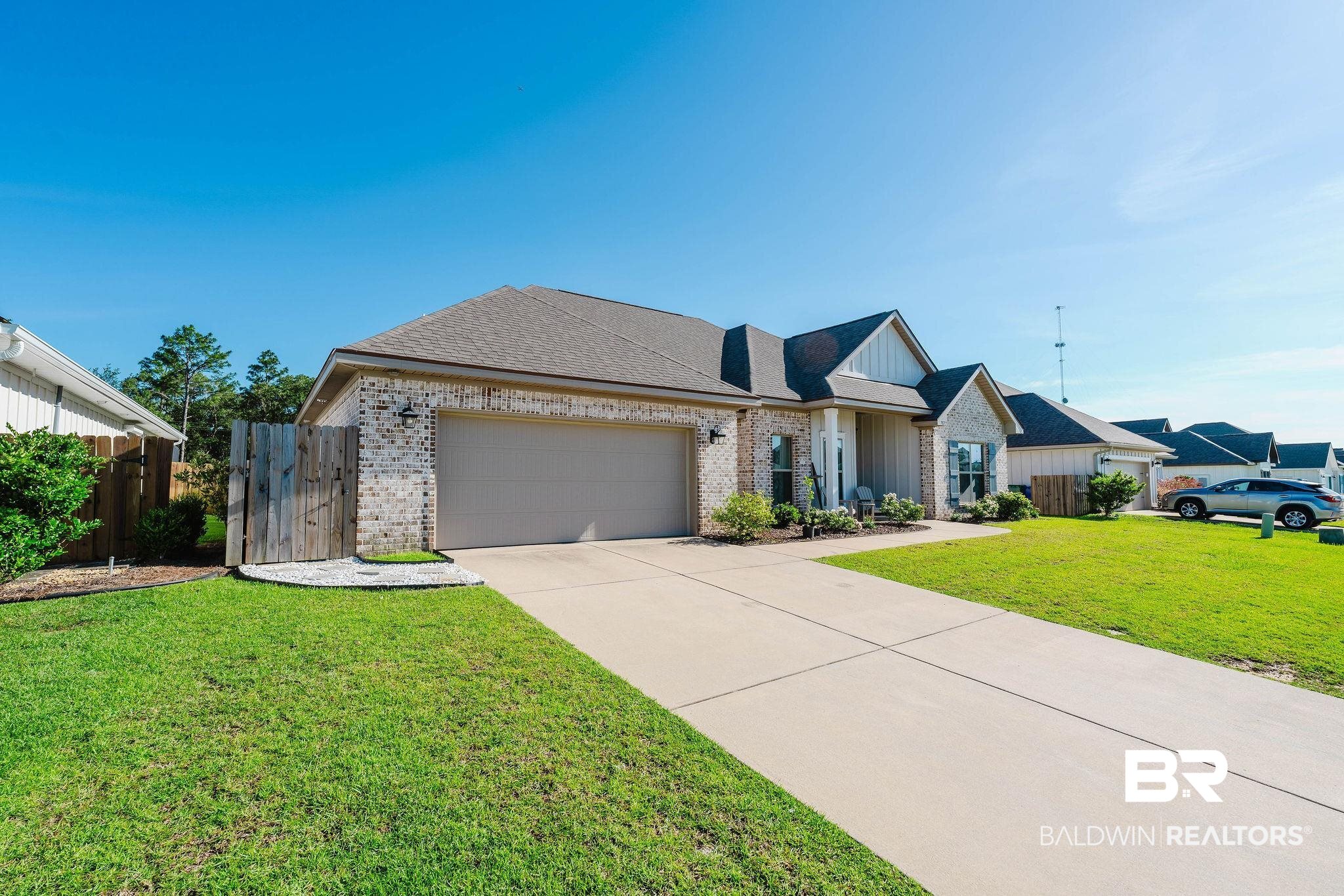 7872 Calverton Street Foley, AL 36535 - Photo 6 of 76 Brick and siding exterior featuring an attached two-car garage with a sectional door, a concrete driveway, and a fenced side yard