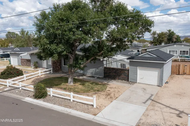 a view of a house with a small yard and large tree
