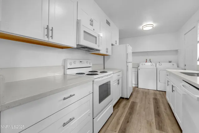 a kitchen with granite countertop white cabinets and white appliances
