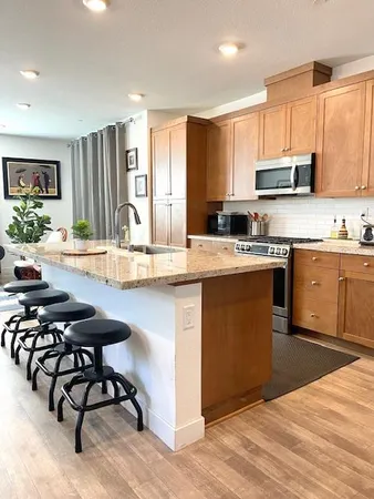 a kitchen with stainless steel appliances granite countertop a stove top oven a sink dishwasher and white cabinets with wooden floor