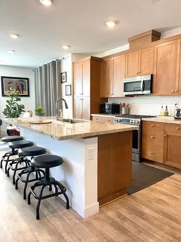 a kitchen with stainless steel appliances granite countertop a stove top oven a sink dishwasher and white cabinets with wooden floor