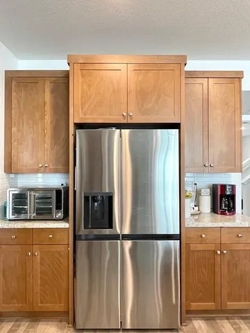 a view of a refrigerator a window and cabinets