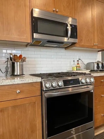 a kitchen with granite countertop a stove top oven microwave and cabinets