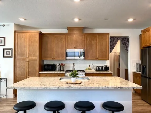 a kitchen with kitchen island granite countertop a sink a stove and a refrigerator with wooden floor