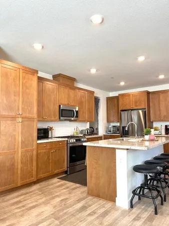 a kitchen with stainless steel appliances kitchen island granite countertop a sink dishwasher a stove and a refrigerator with wooden floor
