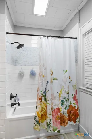 a bath tub sitting next to a white sink and a shower curtain