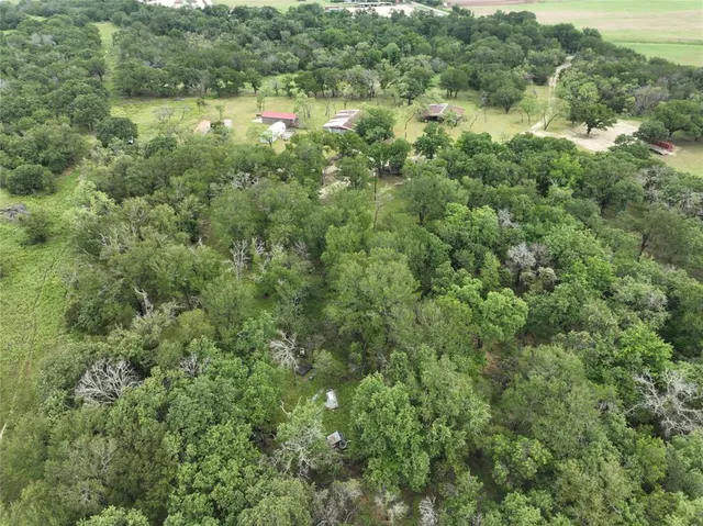 an aerial view of residential houses with outdoor space and trees