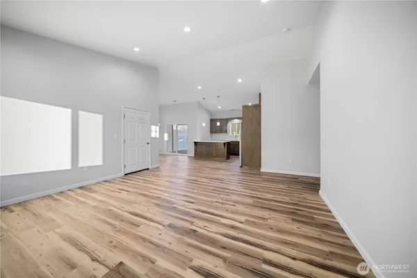 a view of kitchen and empty room with wooden floor