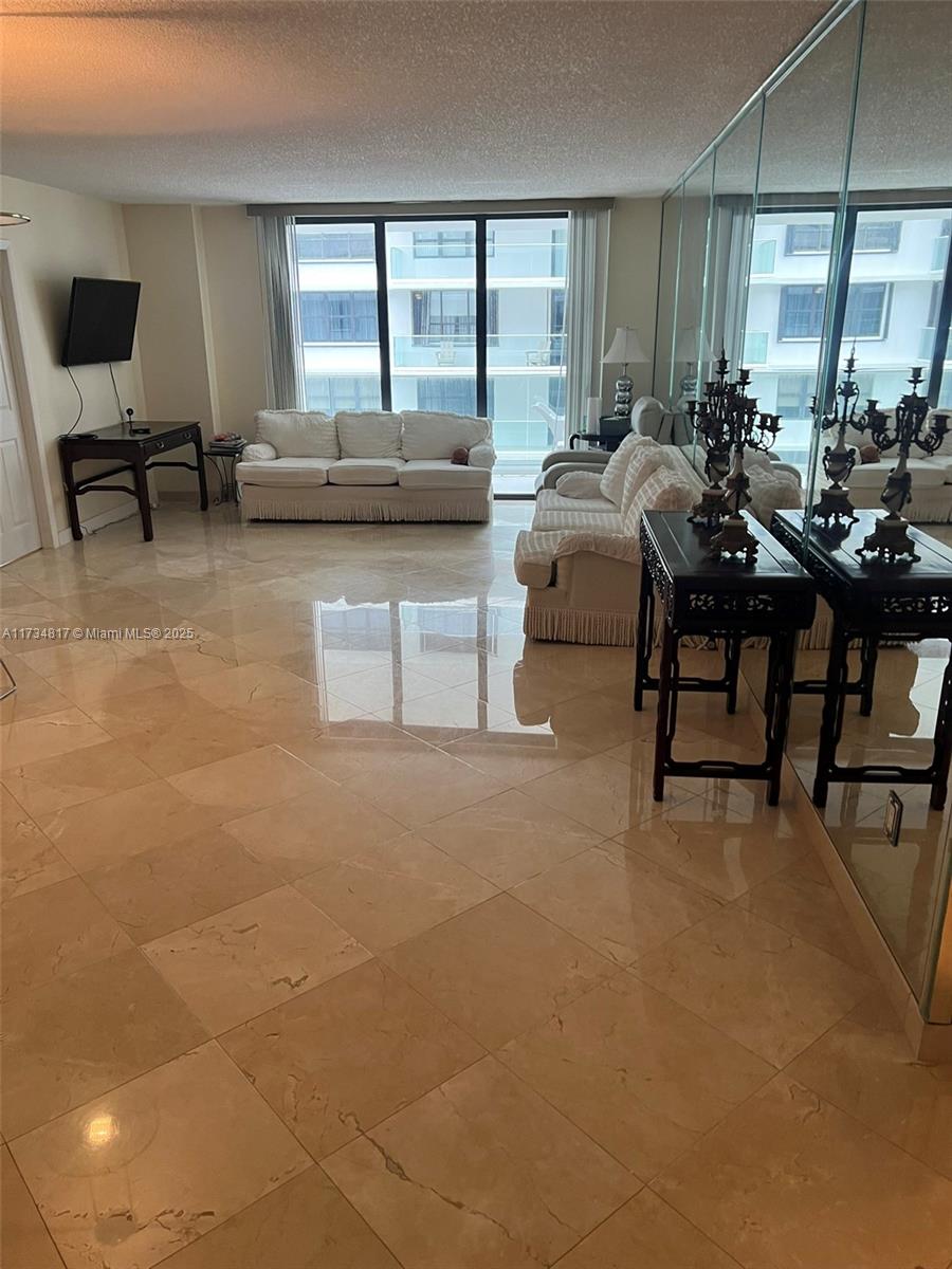 9801 Collins Avenue, Unit 17J Bal Harbour, FL 33154 - Photo 16 of 34 a living room with furniture and a flat screen tv