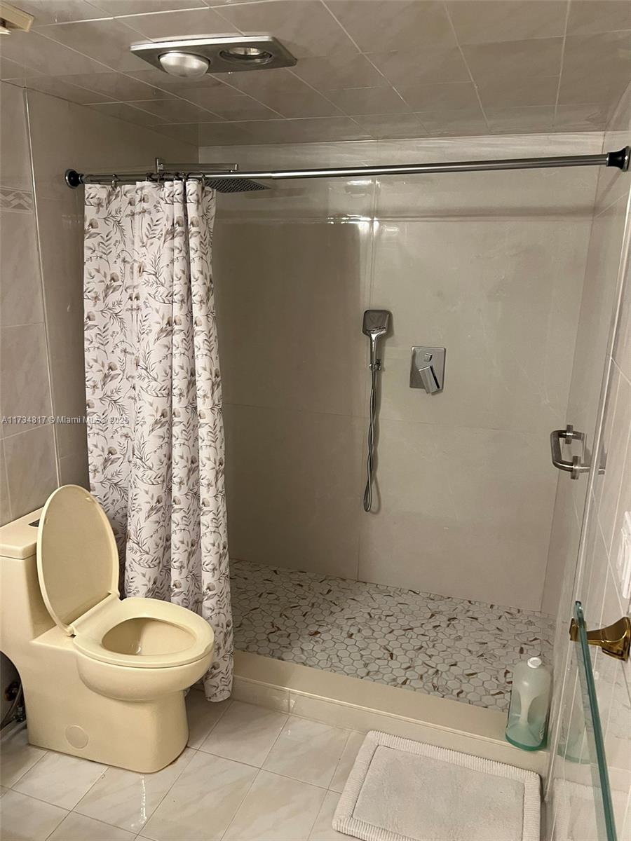 9801 Collins Avenue, Unit 17J Bal Harbour, FL 33154 - Photo 19 of 34 a white toilet sitting next to a shower curtain