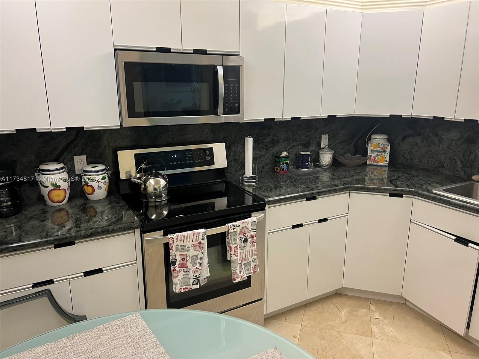 9801 Collins Avenue, Unit 17J Bal Harbour, FL 33154 - Photo 25 of 34 a kitchen with stainless steel appliances granite countertop a stove a microwave and cabinets