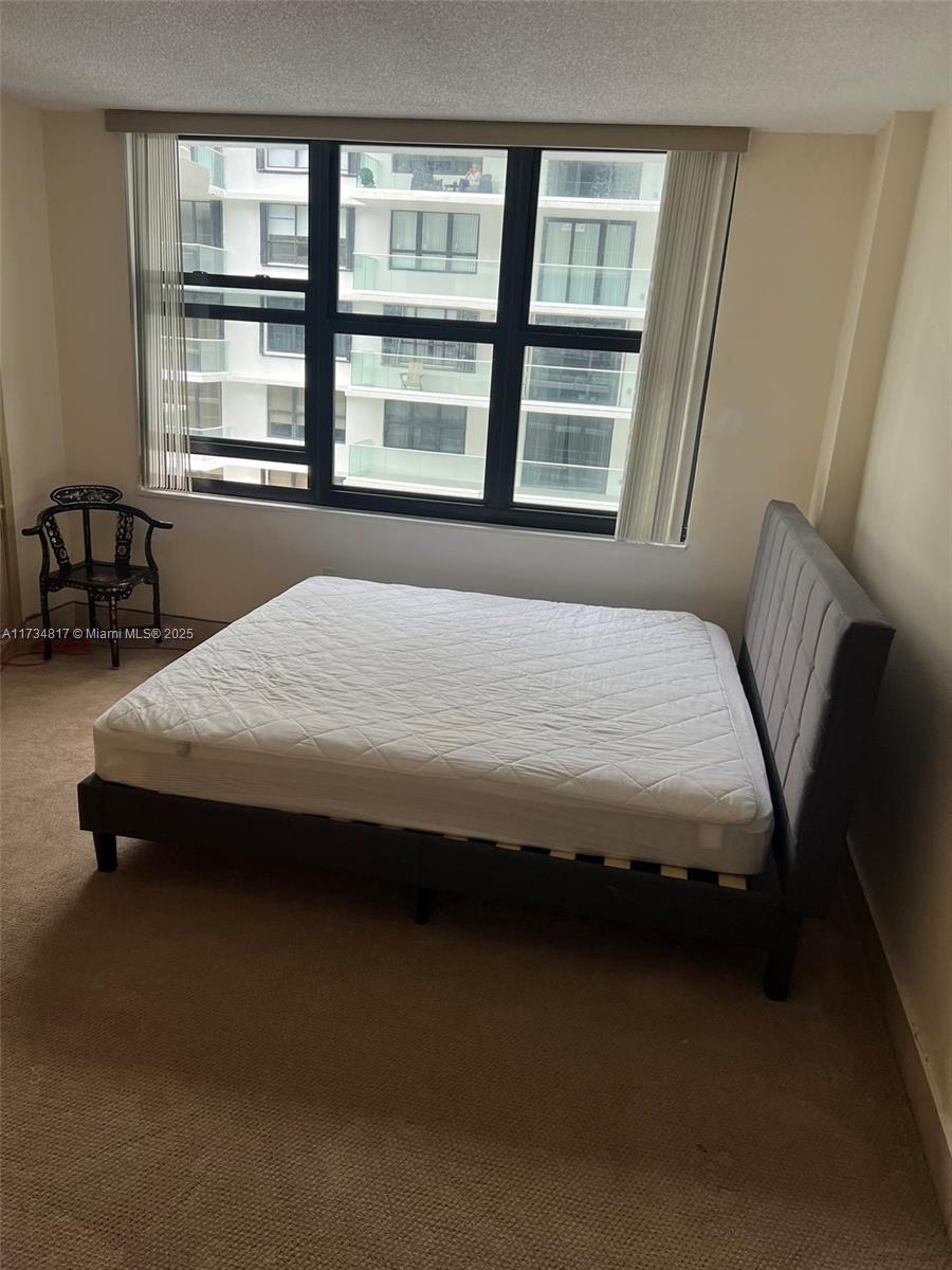 9801 Collins Avenue, Unit 17J Bal Harbour, FL 33154 - Photo 7 of 34 a bedroom with a bed a table and a large window