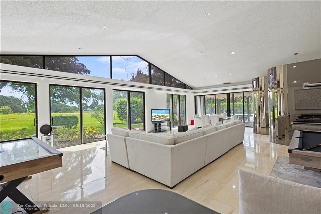 5304 Woodlands Boulevard Tamarac, FL 33319 - Photo 12 of 57 a living room with furniture large windows and a flat screen tv