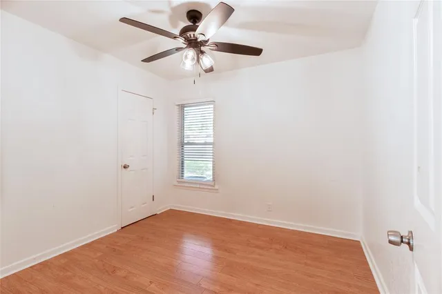 an empty room with a window and a fan