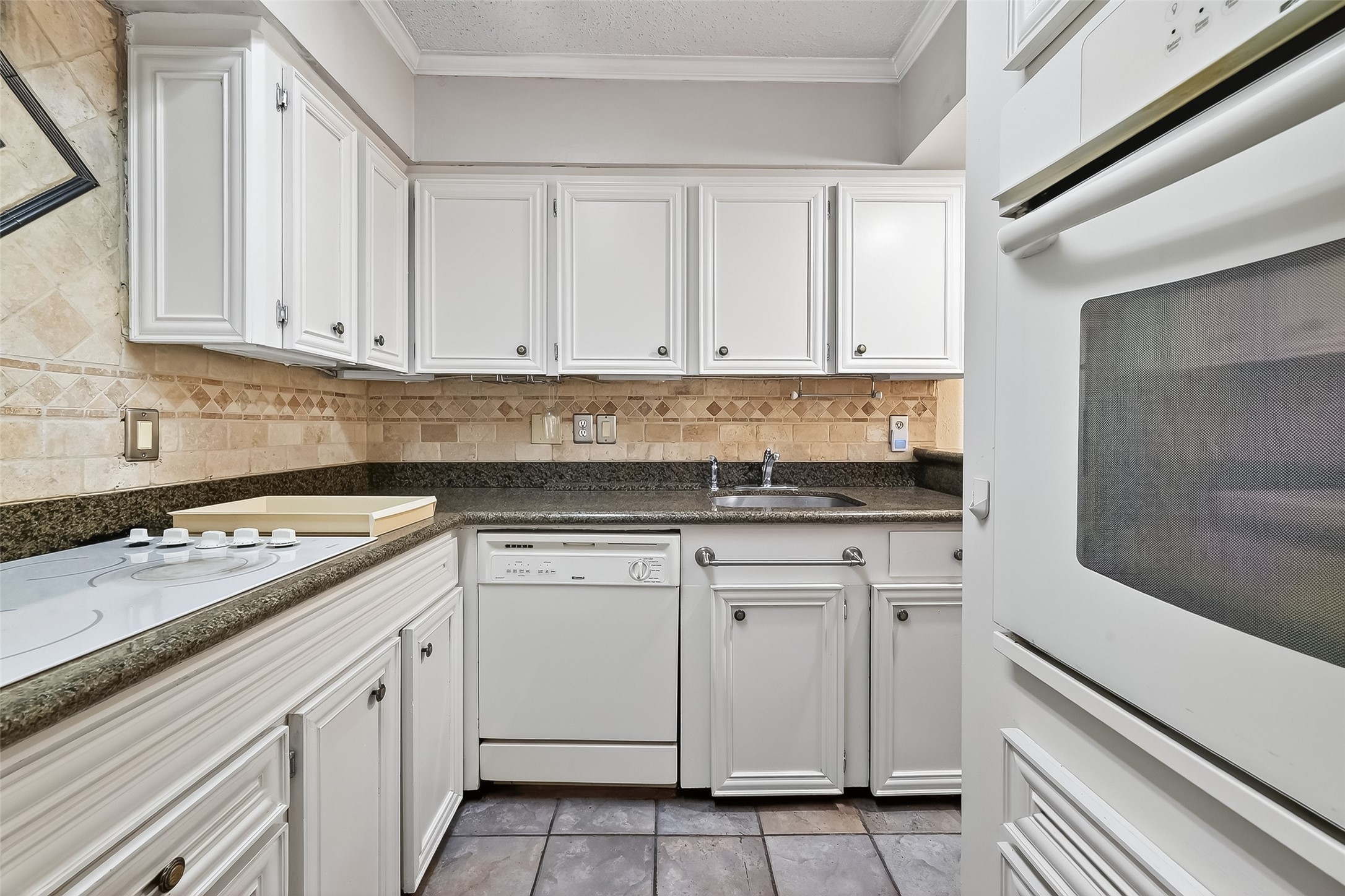 909 Silber Road, Unit 16C Houston, TX 77024 - Photo 12 of 32 a kitchen with granite countertop white cabinets and white appliances