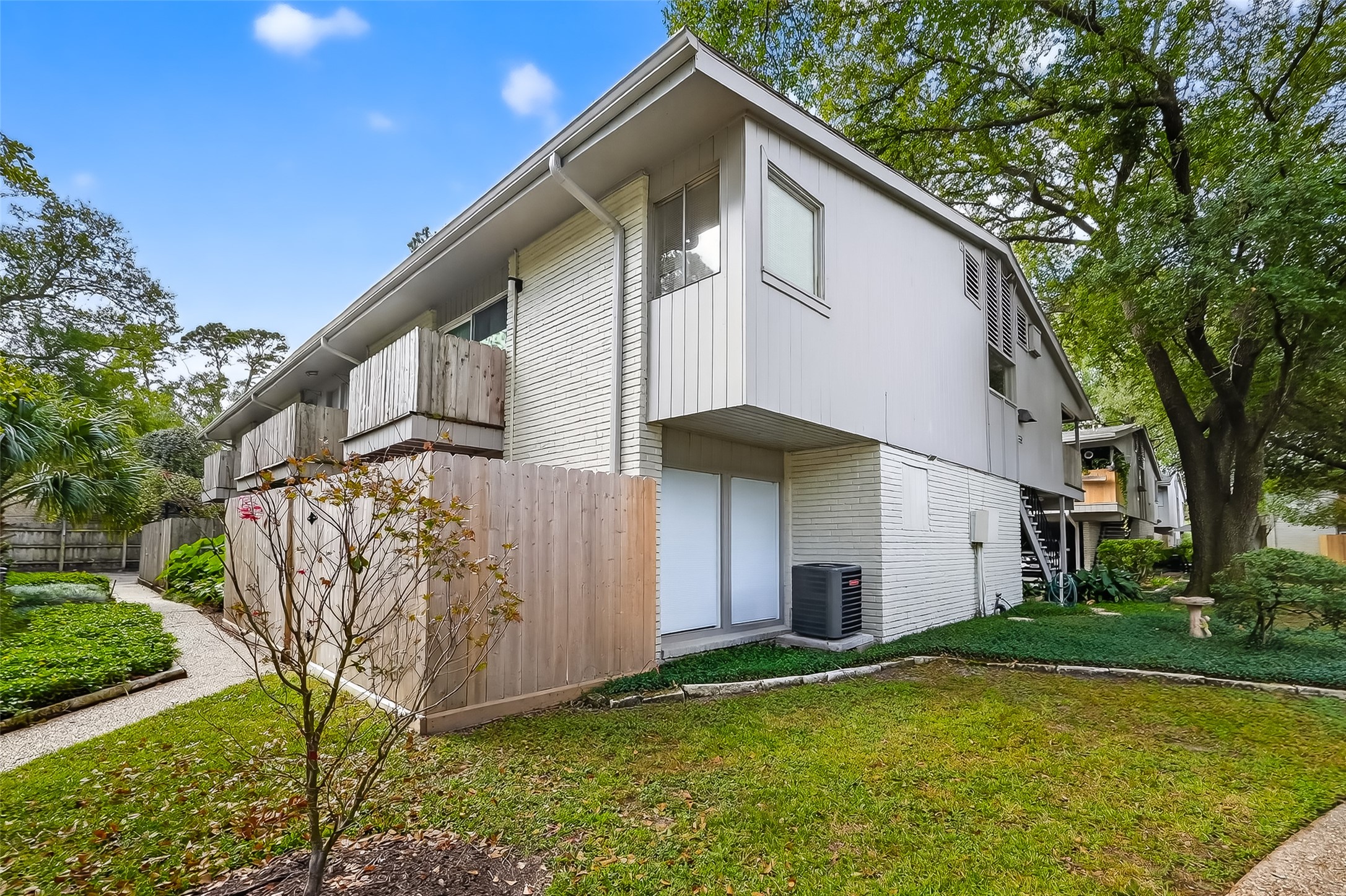 909 Silber Road, Unit 16C Houston, TX 77024 - Photo 29 of 32 a view of a white house with a yard and plants