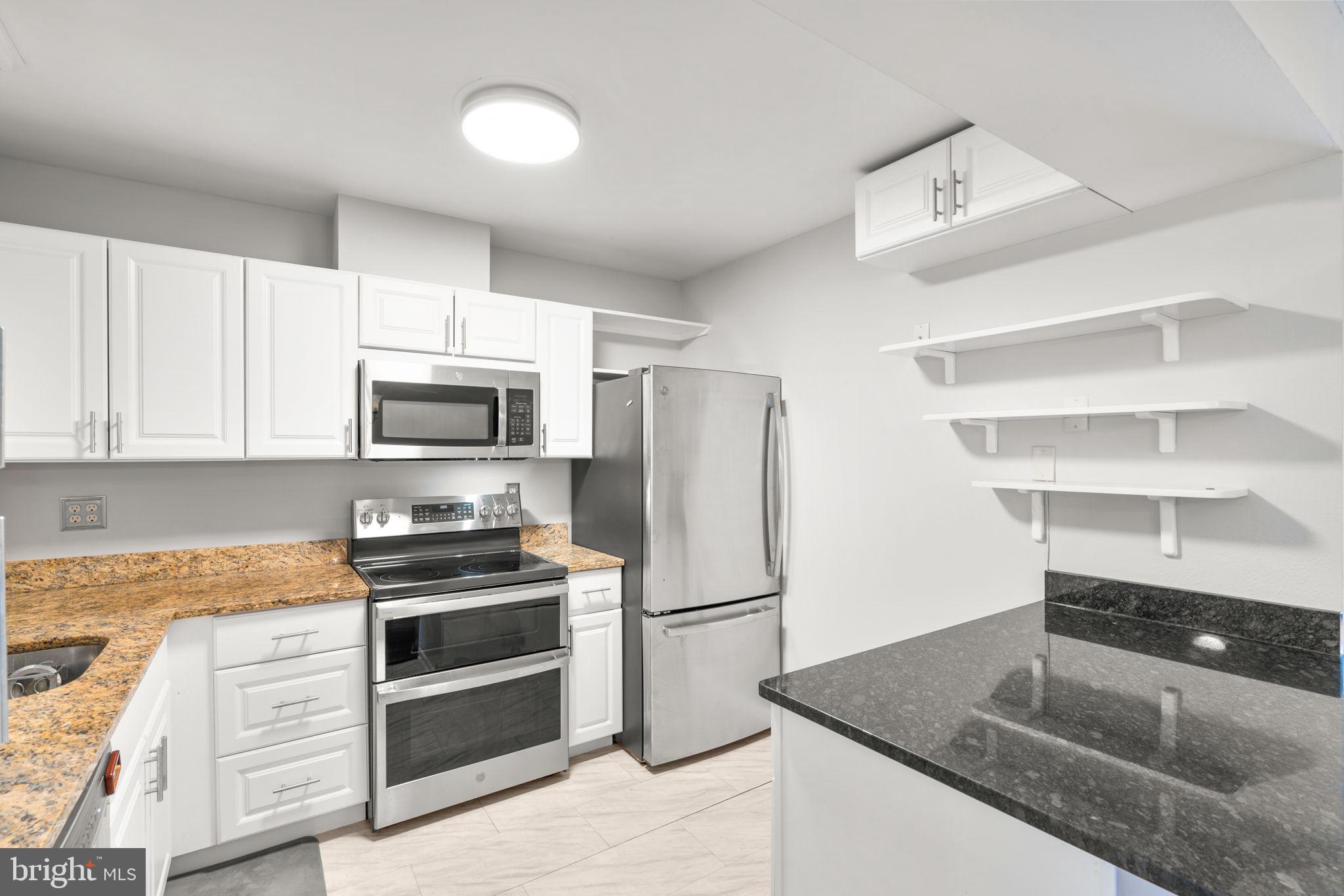 3415 Island Creek Court, Unit 131A Silver Spring, MD 20906 - Photo 9 of 32 a kitchen with kitchen island granite countertop a stove a sink and a refrigerator