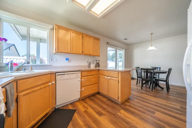 a kitchen with stainless steel appliances granite countertop sink stove and white cabinets with wooden floor