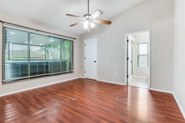 a view of an empty room with wooden floor and a window