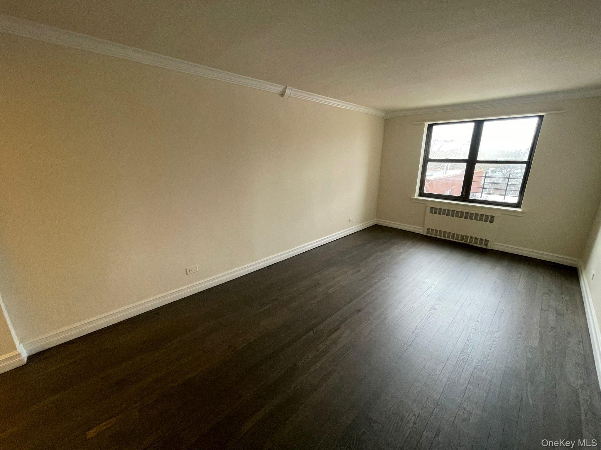 100-11 67th Road, Unit 4 Queens, NY 11375 - Photo 12 of 33 Unfurnished room featuring ornamental molding, dark wood finished floors, and radiator