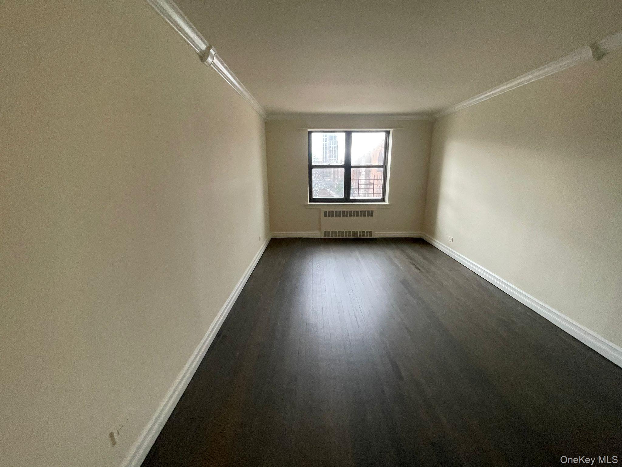 100-11 67th Road, Unit 4 Queens, NY 11375 - Photo 13 of 33 Empty room with crown molding, dark wood-style flooring, and radiator
