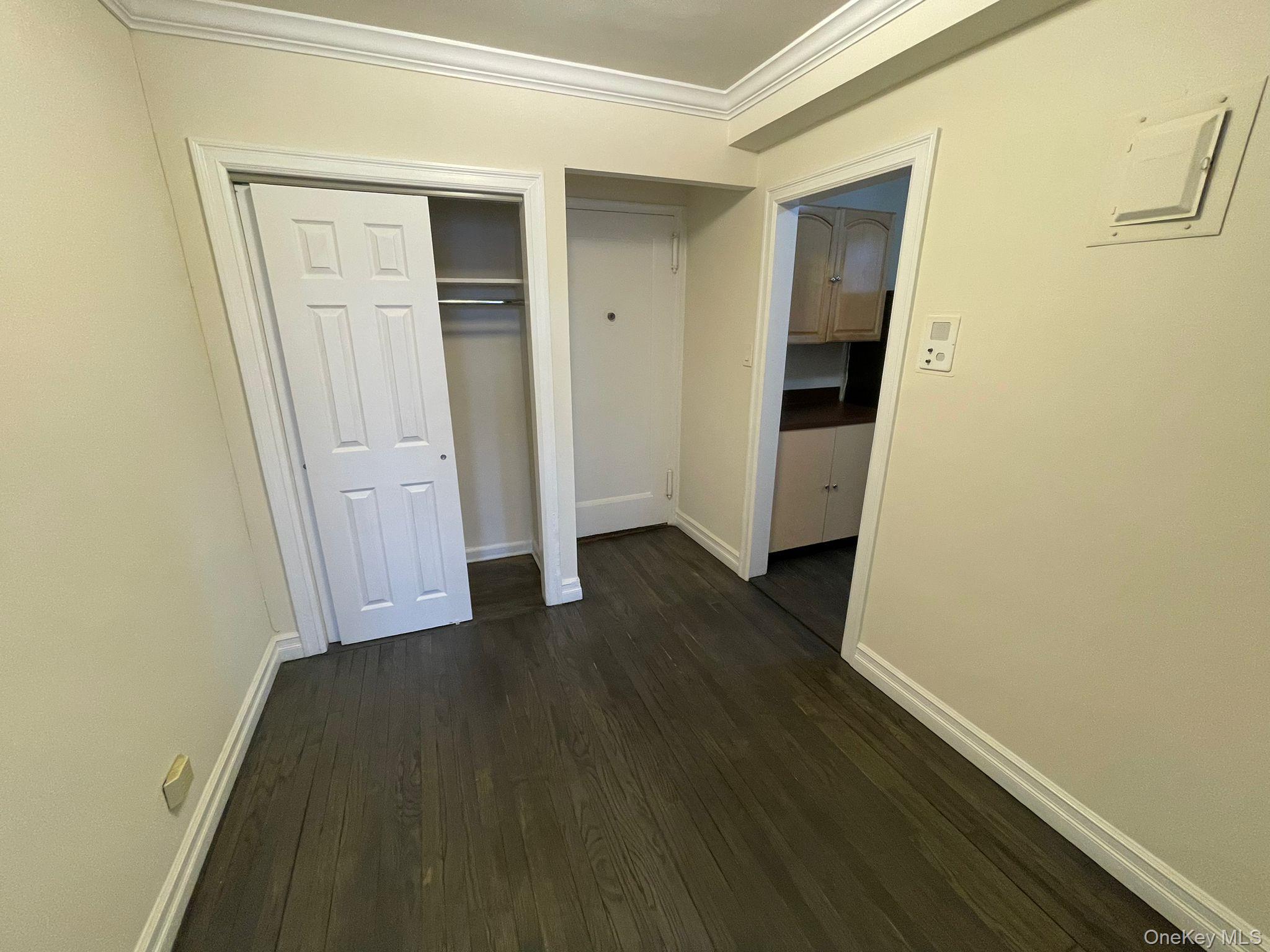 100-11 67th Road, Unit 4 Queens, NY 11375 - Photo 14 of 33 Unfurnished bedroom featuring crown molding, dark wood-style flooring, and a closet