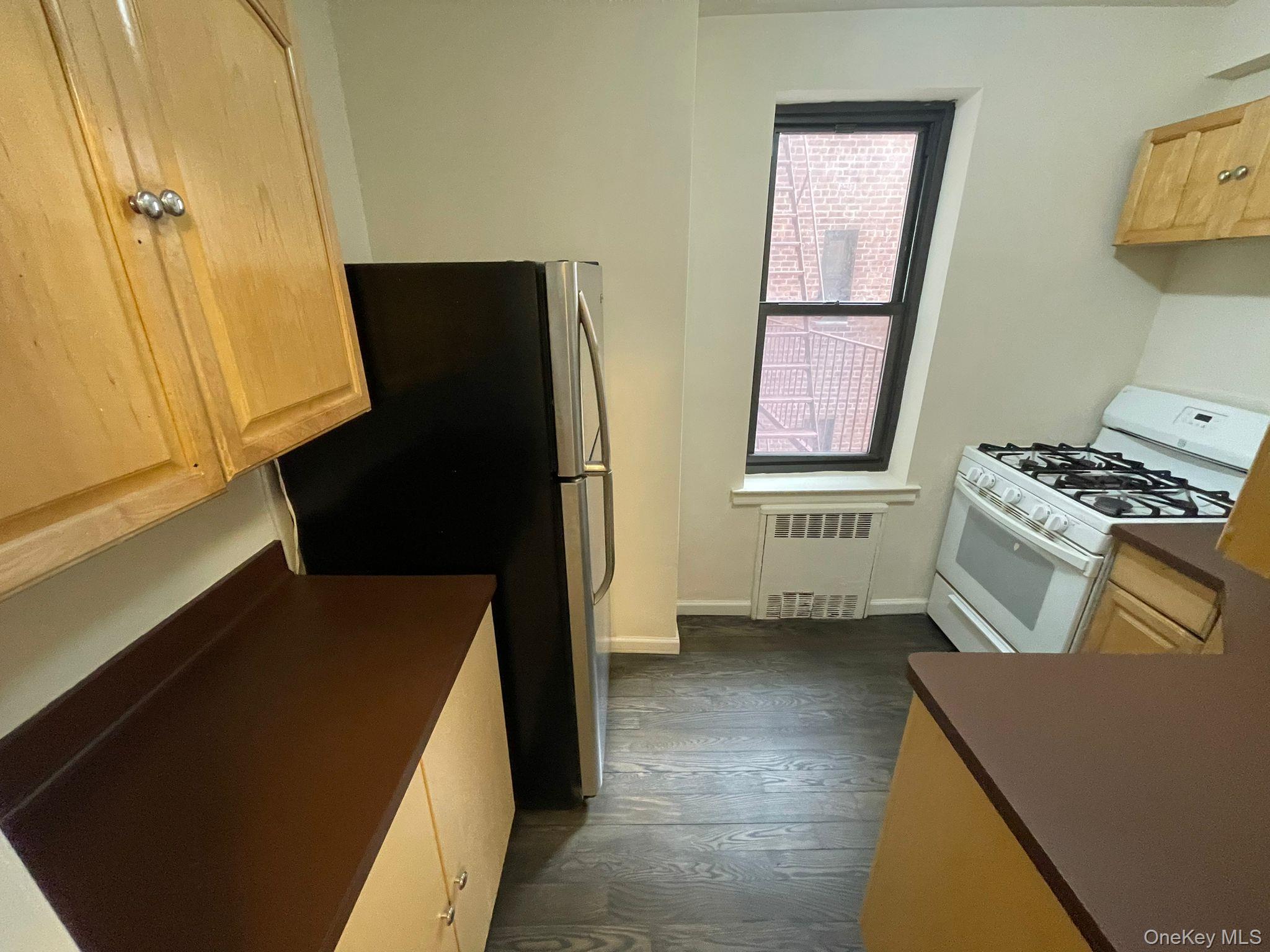 100-11 67th Road, Unit 4 Queens, NY 11375 - Photo 20 of 33 Kitchen with gas range gas stove, dark wood finished floors, light brown cabinets, and radiator heating unit