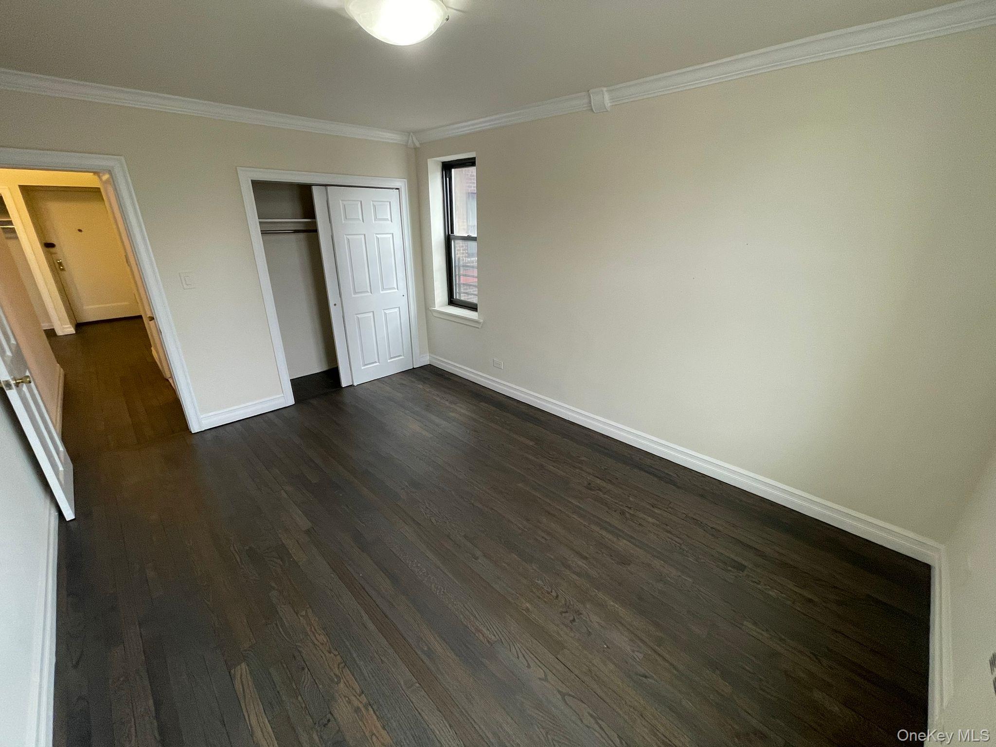 100-11 67th Road, Unit 4 Queens, NY 11375 - Photo 23 of 33 Unfurnished bedroom featuring ornamental molding, dark wood-type flooring, and a closet