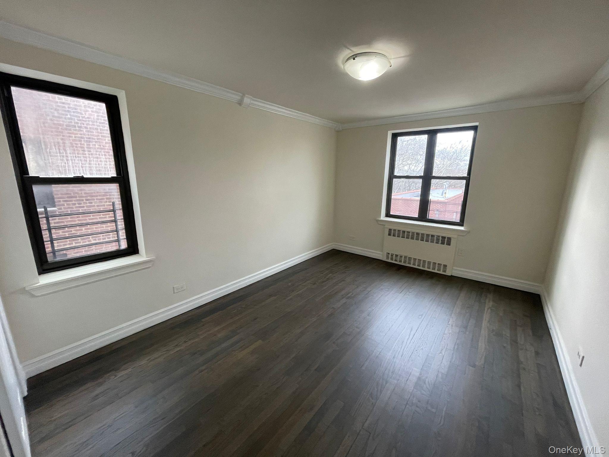 100-11 67th Road, Unit 4 Queens, NY 11375 - Photo 24 of 33 Empty room featuring ornamental molding, dark wood-style floors, and radiator