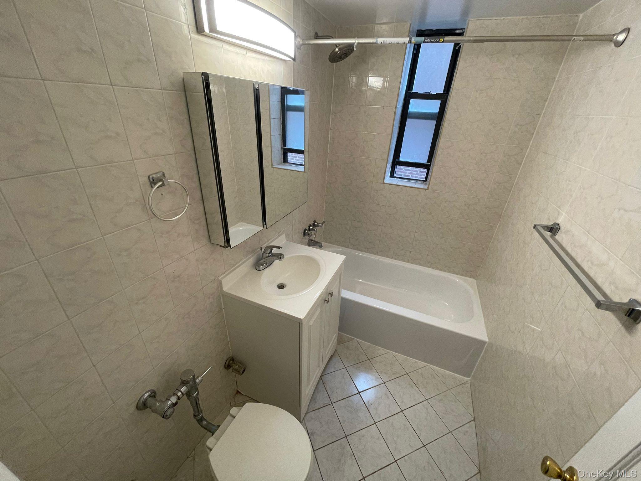 100-11 67th Road, Unit 4 Queens, NY 11375 - Photo 26 of 33 Full bathroom with tile walls, vanity, shower / bath combination, and light tile patterned floors