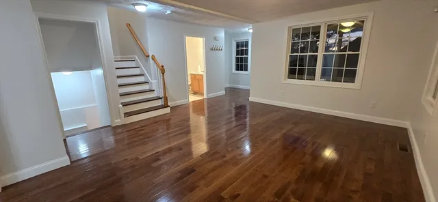 a view of an empty room with wooden floor and stairs