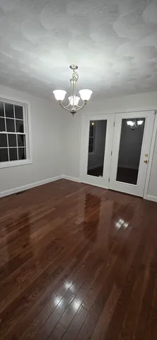 a view of an empty room with wooden floor and a ceiling fan