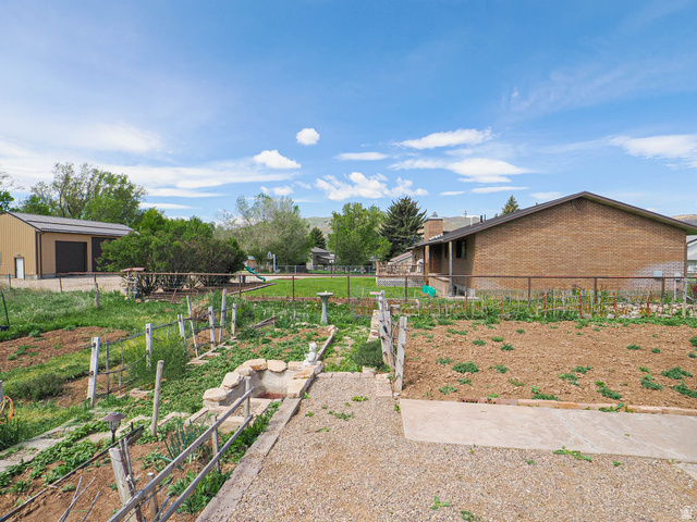 94 Spring Canyon Road Coalville, UT 84017 - Photo 10 of 50 Expansive backyard featuring multiple garden beds, a concrete patio, and a gravel pad