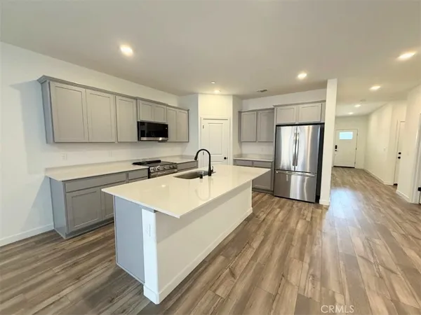 a large white kitchen with wooden floor and a sink
