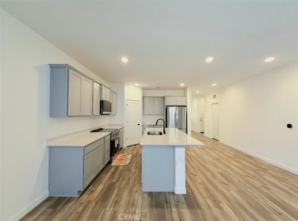 a large room with kitchen island a sink wooden floor and stainless steel appliances