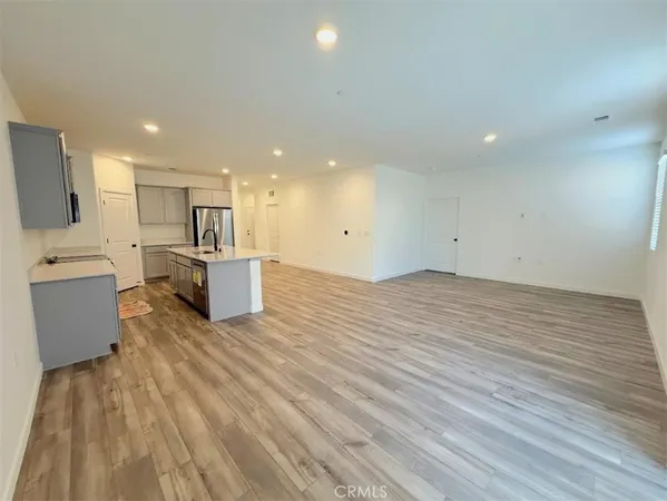 a big room with stainless steel appliances wooden floor and view living room