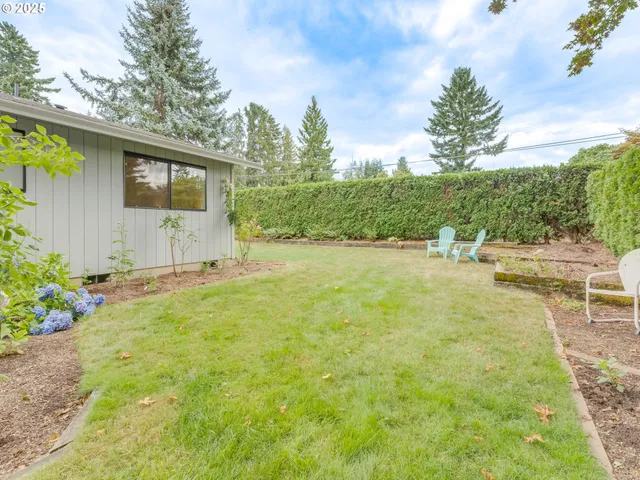 a backyard of a house with table and chairs plants and large trees